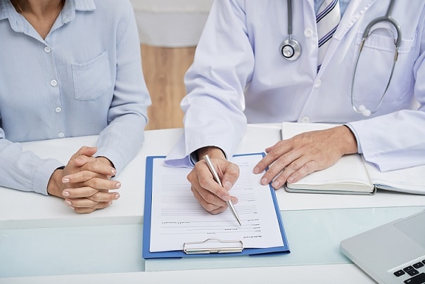 médico conversando com paciente sobre espiritualidade e mostrando no papel o que deve ser feito
