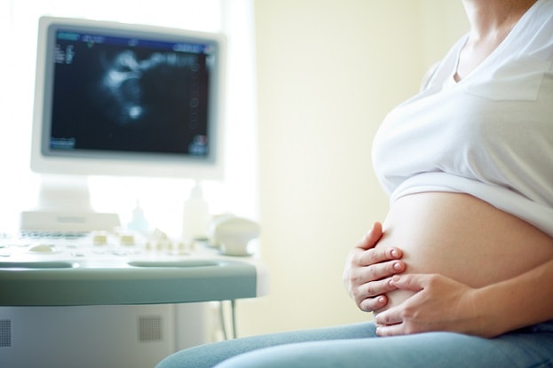 mulher grávida em frente ao monitor da ultrassonografia em consulta de rotina para avaliar doenças renais