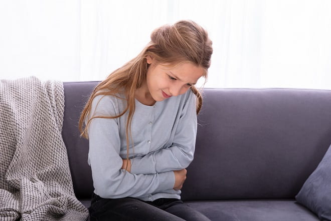 menina com as mãos na barriga devido à dismenorreia