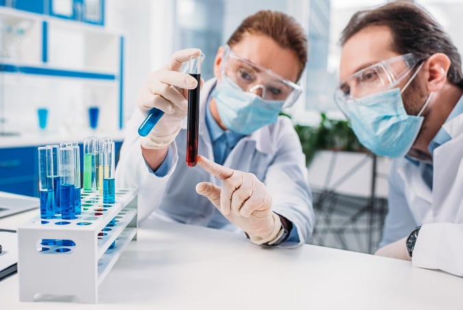 médicos laboratoristas avaliando tubo com sangue em point-of-care testing