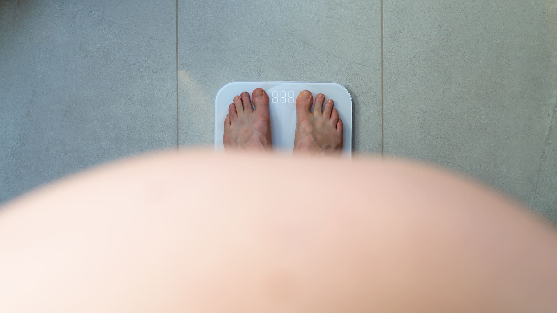 Pessoa obesa se pesando na balança como estratégia para manutenção do peso perdido