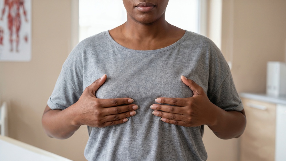 Mulher negra com as mãos sobre os seios, representando o câncer de mama em mulheres negras